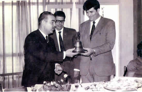 Foto: Día Fundación del Rotary Club Rocha Este. El presidente del Club padrino, Rotary Rocha, Julio Sivera, y el compañero de Directiva,  Esc.  Walter Hutton, entregan al Primer Presidente del Rotary Club Rocha Este, Dr.Ismael Correa Miraphalete, la campana.