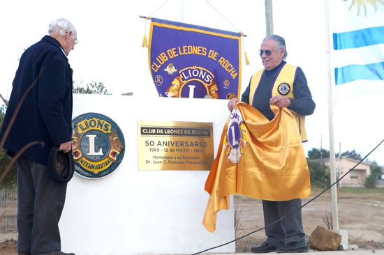 León Pablo Enrique Pertusso, Presidente del Club de Leones de Rocha, y Escribano José Ramón Luna Pradere, que fueran fundadores del Club de Leones de Rocha, descubren la plaqueta en homenaje al Dr. Juan Carlos Pertusso Pasaqualetti, en la Plazoleta que lleva su nombre.  